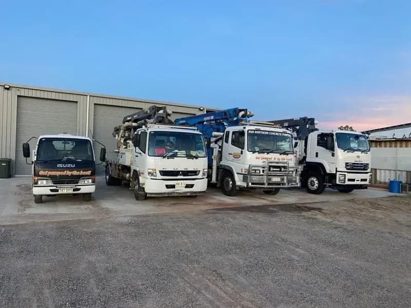 Four White Trucks Parked in Front of a Gray Building — Far Northern Concrete Pumping, servicing Tully QLD