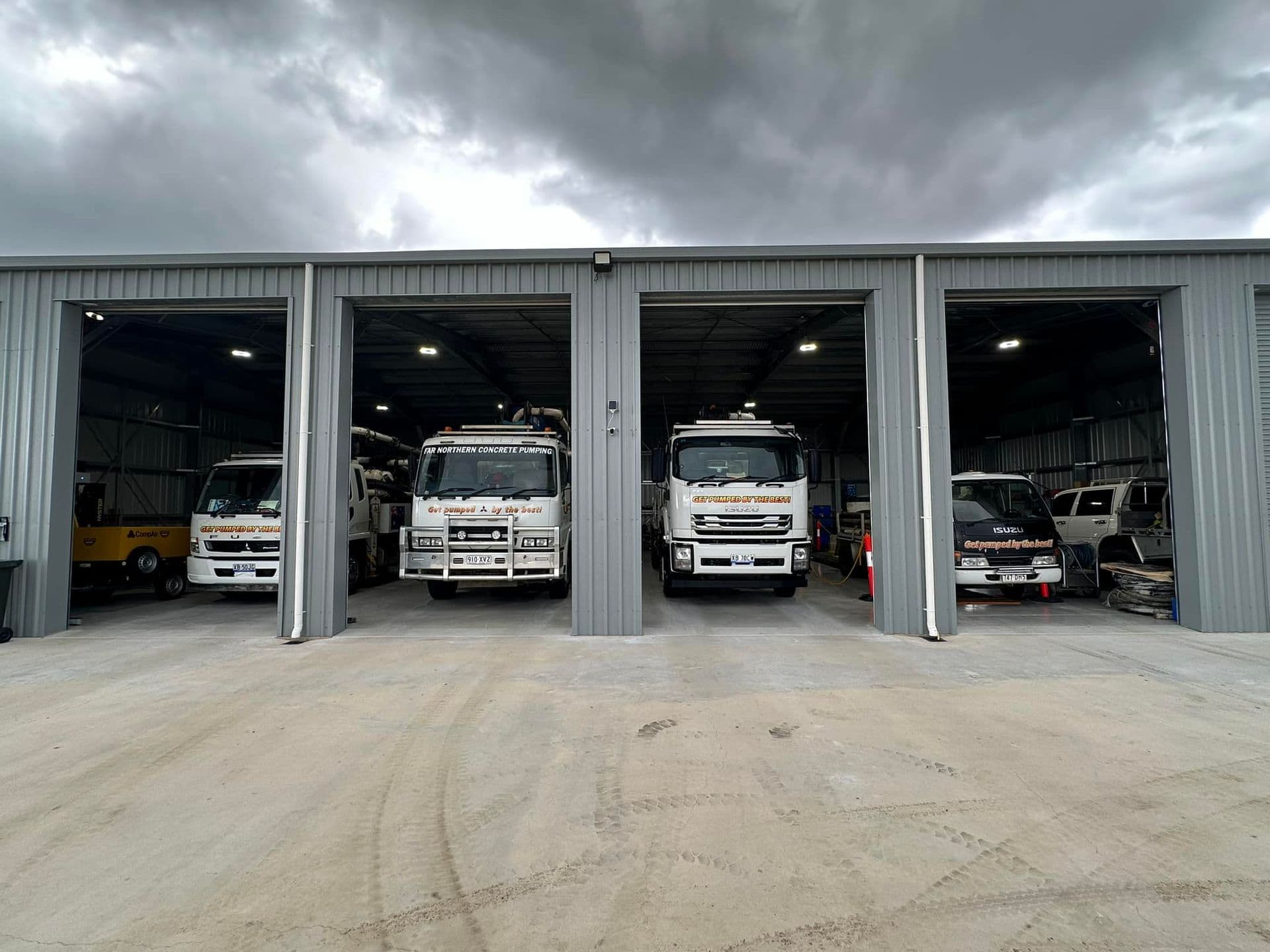 Far Northern Concrete Pumping workshop bay with parked concrete pump trucks