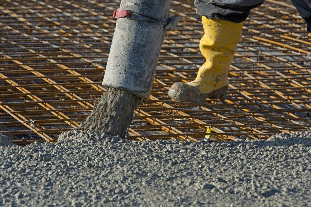 Concrete Being Poured Over Rebar Grid by a Worker in Yellow Boot — Far Northern Concrete Pumping in Cairns, QLD